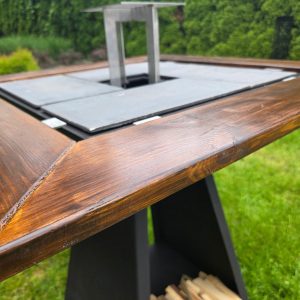 Zdjęcie z bliska przedstawia blat grilla. Widać także płyty żeliwne, ruszt stalowy oraz fragment nogi grilla.