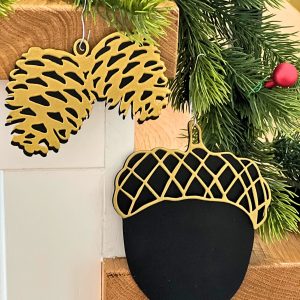 Duża bombka w kształcie czarno złotego żołędzia. Jest to wycinana laserowo ozdoba świąteczna.