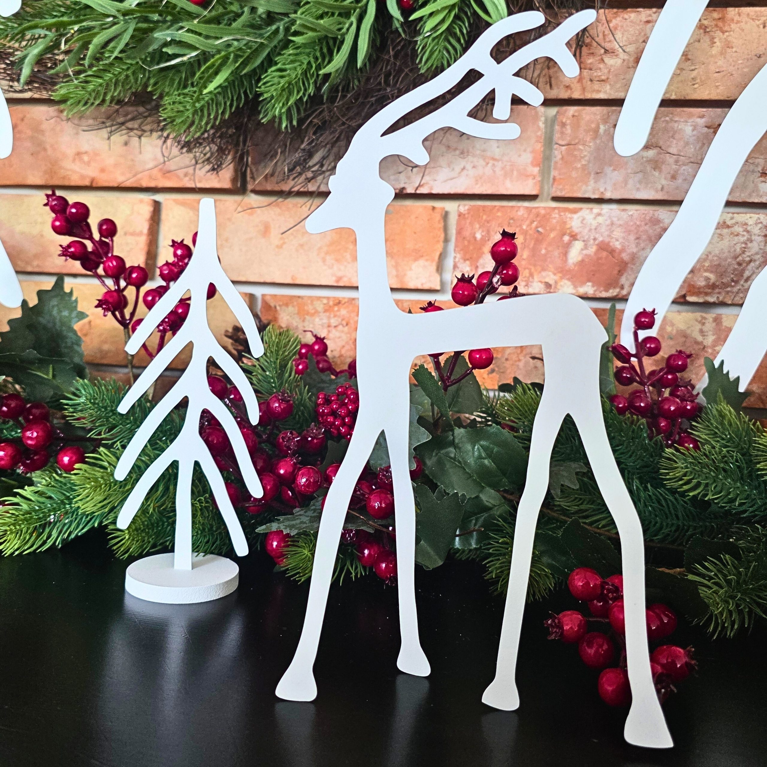 Zdjęcie przedstawia ozdobę świąteczną renifera. W tle widać jarzębinę oraz stroik świąteczny.