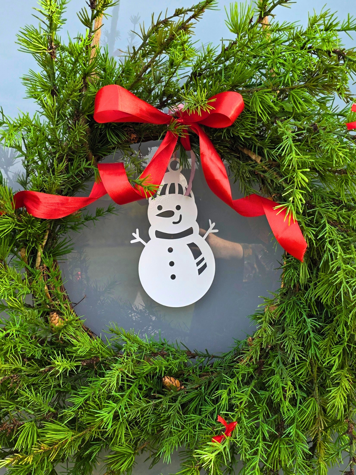 Zdjęcie przedstawia bombkę bałwanka wykorzystanego jako część dekoracji świątecznego wianka.