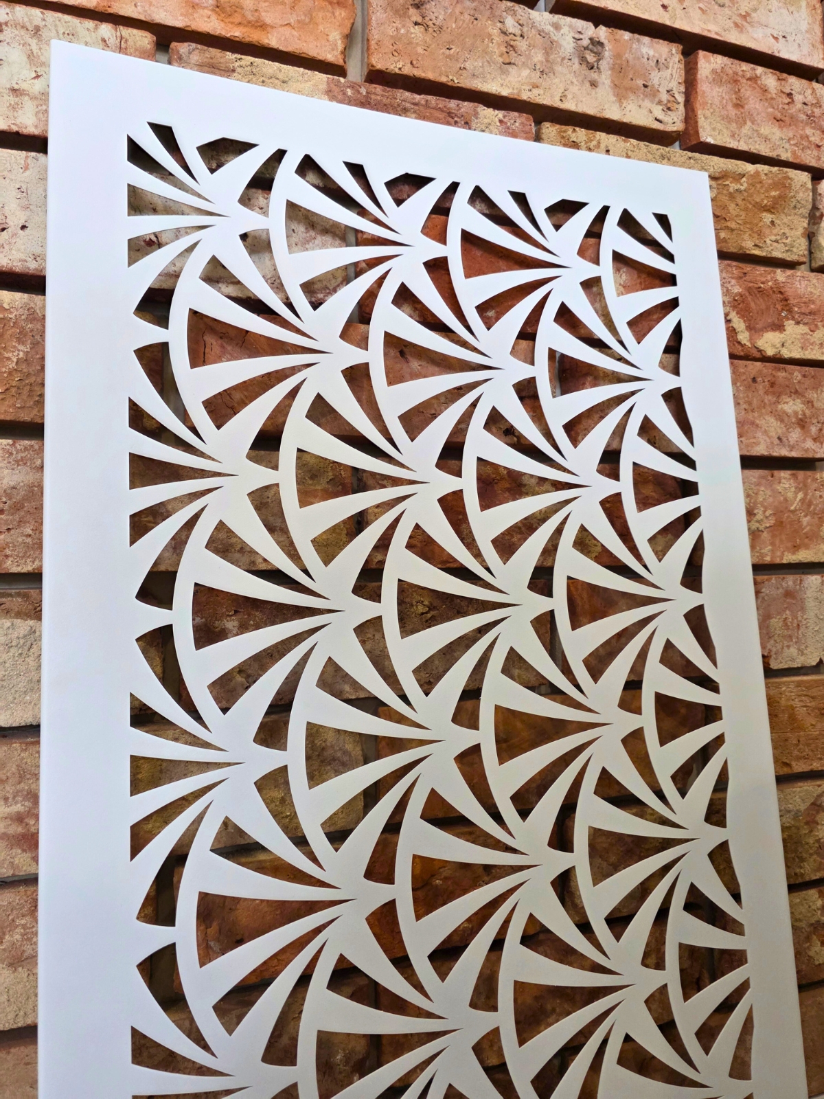 Prostokątny panel z delikatnym, geometrycznym wzorem wyciętym w białej powierzchni.