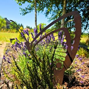 Rdzawy motyl-ogrodowa ozdoba otoczona fioletowymi kwiatami i letnią zielenią.